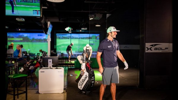A man is standing in front of a golf simulator.
