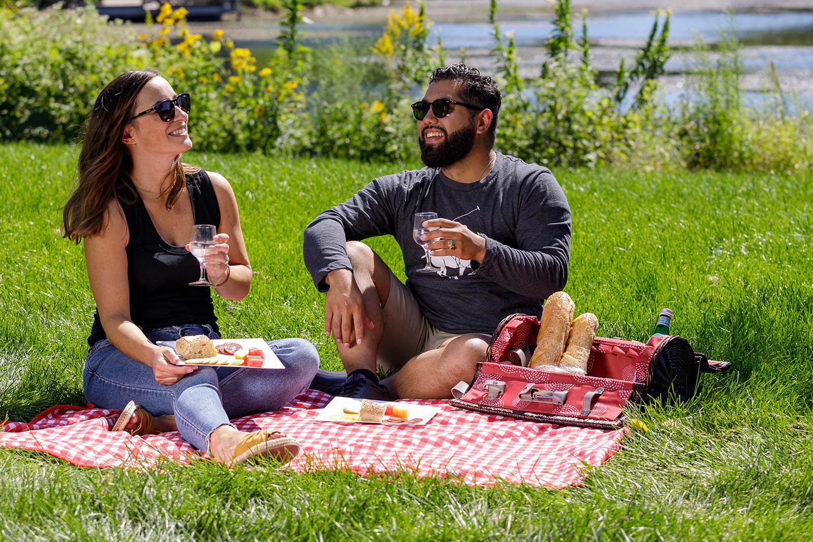 a man and a woman sitting on a blanket eating food