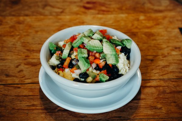 a white bowl filled with a salad on top of a wooden table.