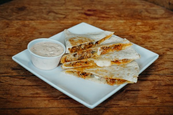 a white plate topped with quesadillas and a cup of dip.