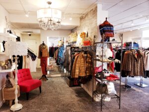 a clothing store with a red chair and a chandelier