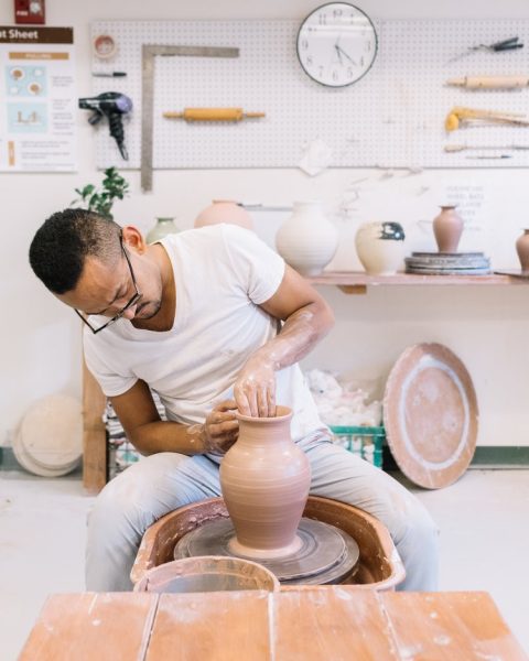 A man is making a pot in a pottery studio.