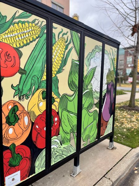 Bus stop shelter with colorful vegetable illustrations including peppers, corn, and eggplant.