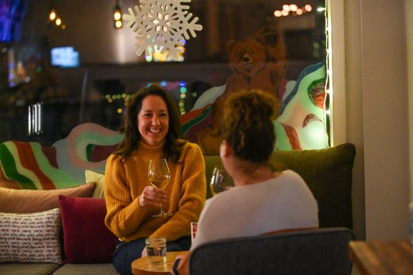 Two women sitting on a couch drinking wine.