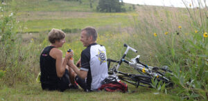 a man and a woman sitting next to a bike