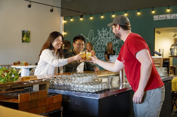 A group of people at a bar with a glass of beer.