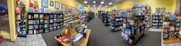 A wide-angle view of a family-friendly game store displays shelves brimming with board games, puzzles, and toys. Bright overhead lights illuminate the spacious interior with yellow walls and a tiled floor, creating an inviting atmosphere for all ages.