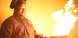 a man in a chef's coat holding a frying pan