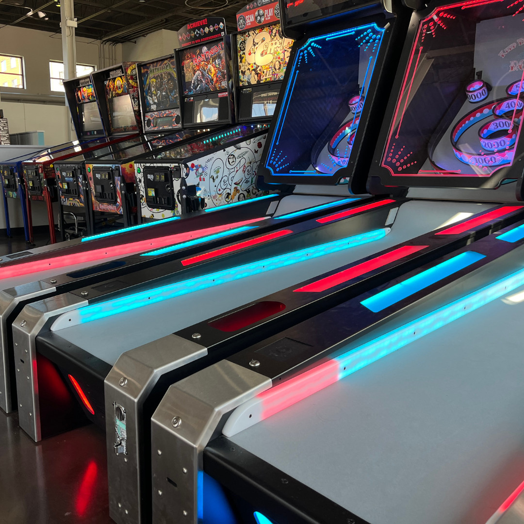 Arcade with skee-ball lanes in the foreground and pinball machines in the background.