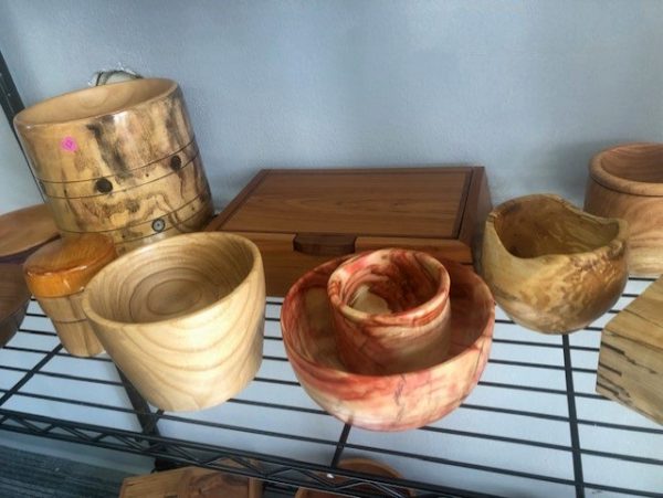 Various wooden bowls and mugs on a rack.