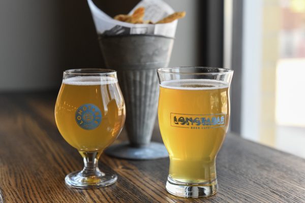 Two glasses of beer on a wooden table.