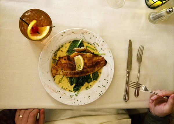 A plate of fish and a drink on a table.