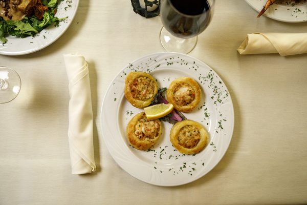 A plate of appetizers and a glass of wine on a table.