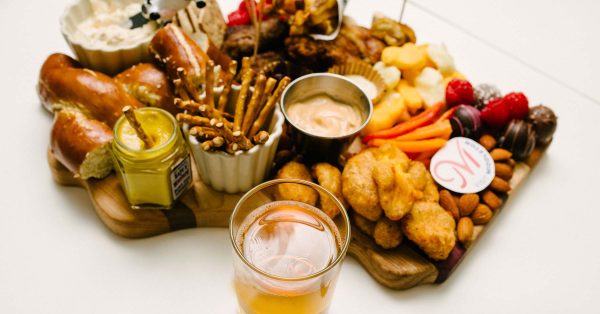 A Wisconsin-shaped charcuterie board with Middleton favorites, and a glass of beer.