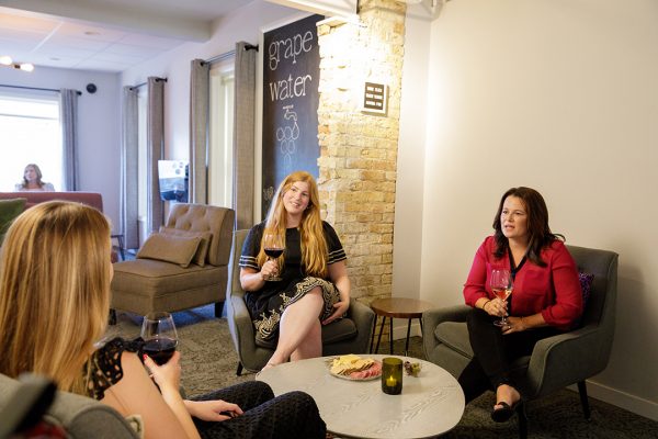 A group of women sitting in a room drinking wine.