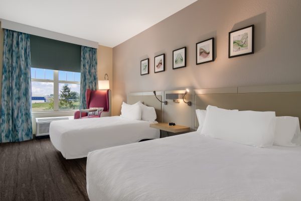 A hotel room with two beds and a window.