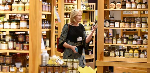 a woman standing in front of a shelf filled with jars.