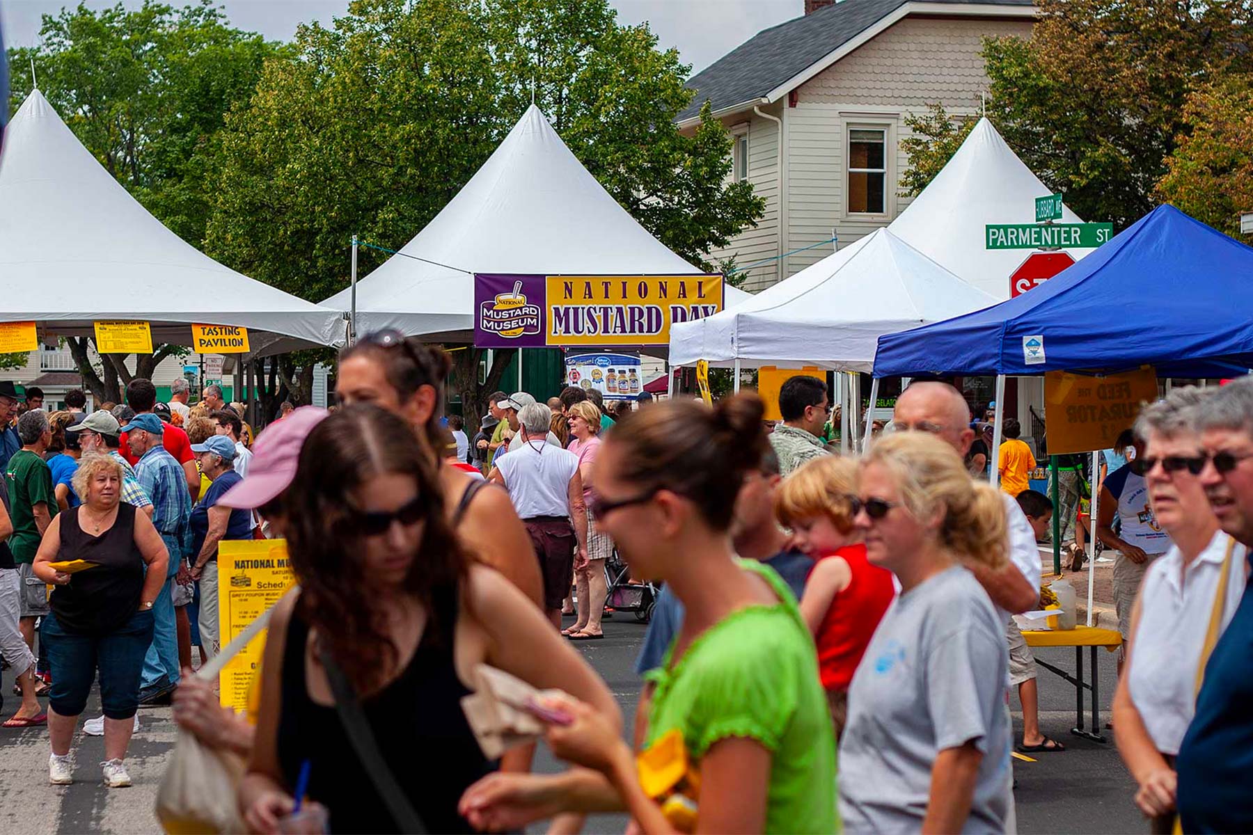 a crowd of people walking around a street next to tents