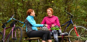 a couple of women sitting on top of a wooden bench