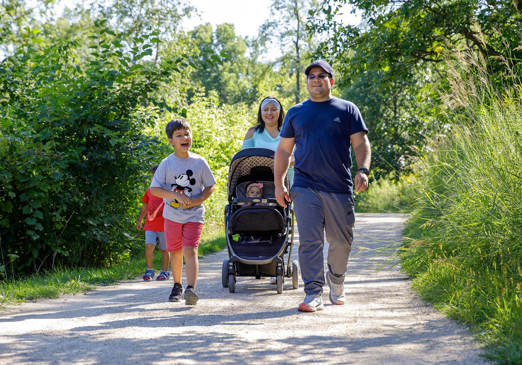 a man and two children walking down a path with a stroller