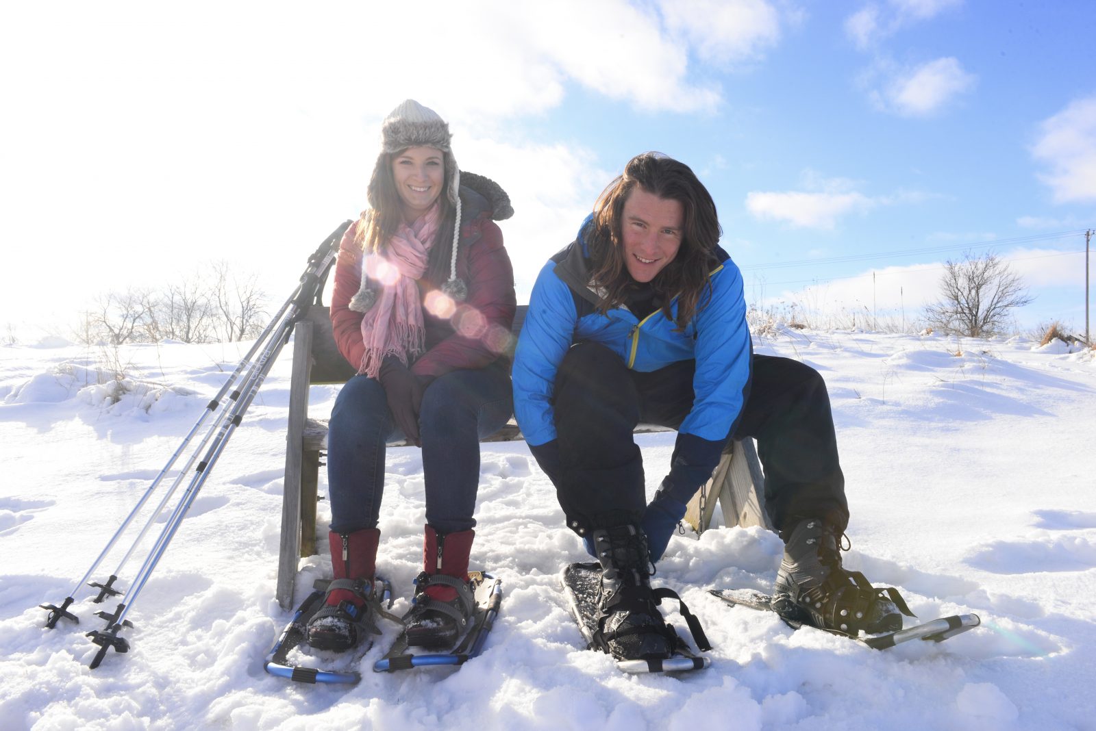 Two people sitting on a bench in the snow.