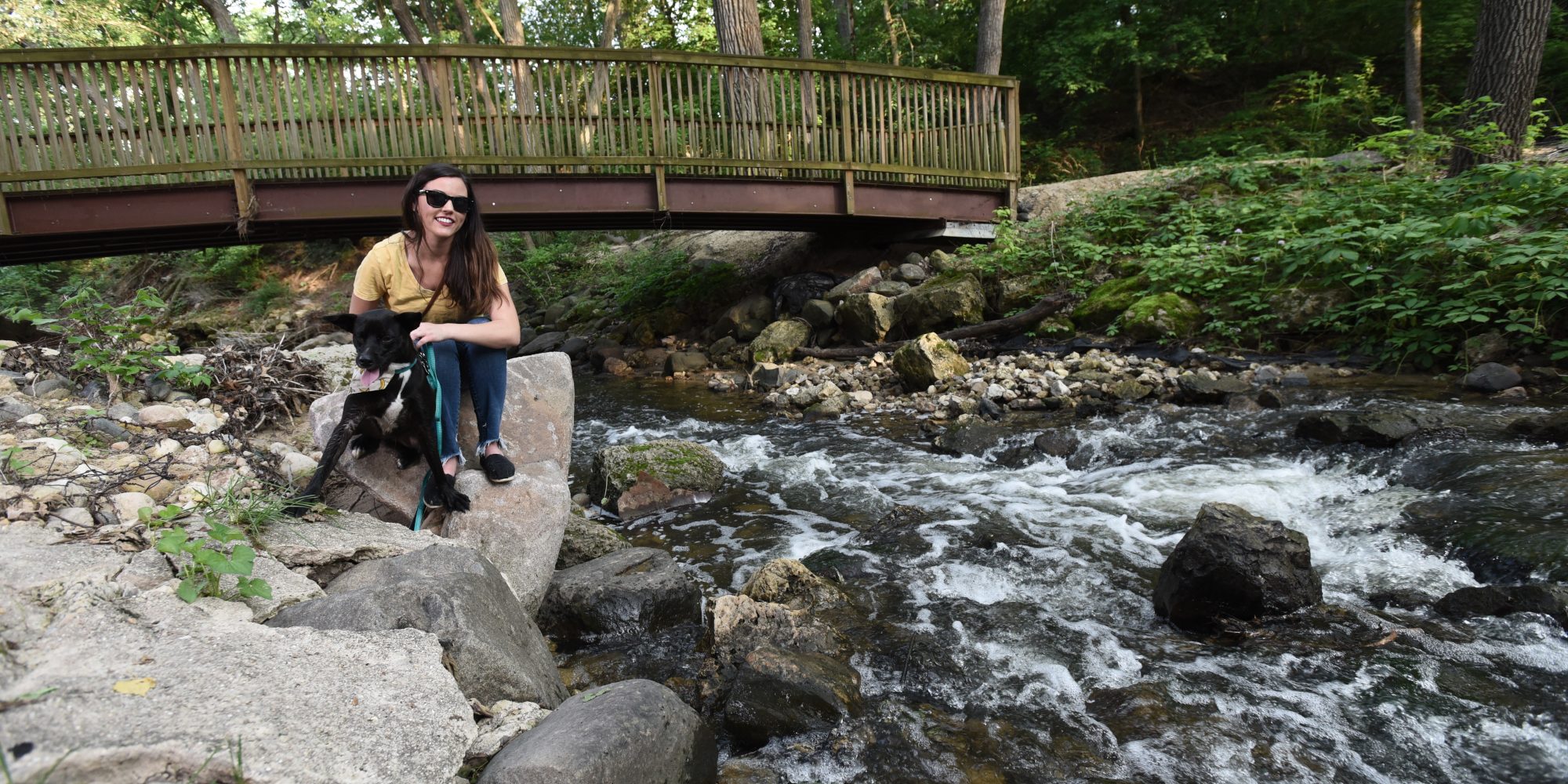 a woman sitting on a rock next to a river