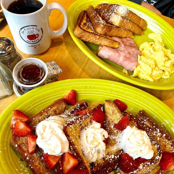 A plate of french toast with strawberries and whipped cream.