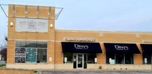 a store front with a clock tower in the background
