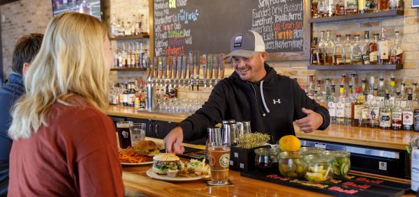 A group of people at a bar with a bartender.