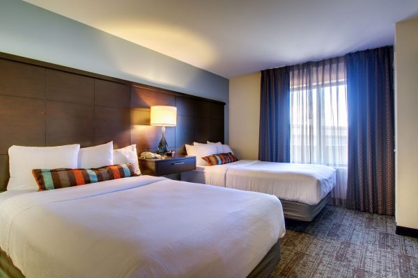 A hotel room with two beds and a television.