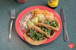 a plate with three tacos and rice on it