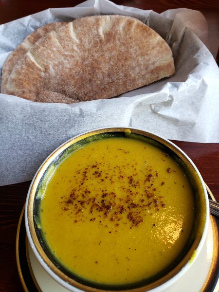 A bowl of soup on a wooden table.