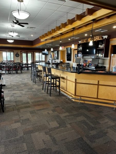 A bar area with stools and a ceiling fan.